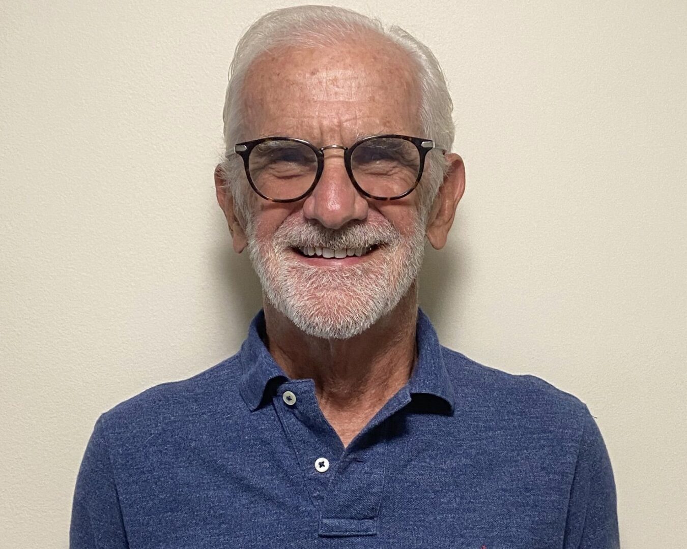A man with white hair and glasses smiling for the camera.